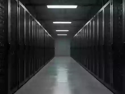 Ein langer, leerer Flur in einem Rechenzentrum mit dunklen Serverracks, die in einer kühlen, professionellen Atmosphäre stehen. - Foto: über boerse-global.de