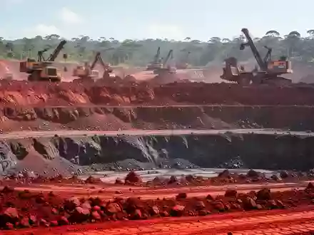 Offene Mine für Seltene Erden in Brasilien mit roter Erde und Bergbaumaschinen im Tageslicht. - Foto: über boerse-global.de