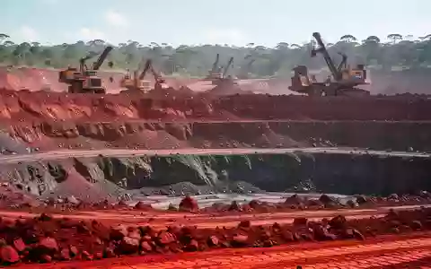 Offene Mine für Seltene Erden in Brasilien mit roter Erde und Bergbaumaschinen im Tageslicht. - Foto: über boerse-global.de