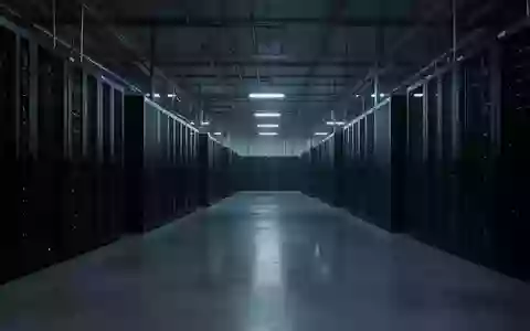 Ein industrieller Serverraum in kühlem, blauem Licht mit dunklen Serverracks in einer minimalistischen, menschenleeren Umgebung. - Foto: über boerse-global.de