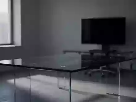 Ein minimalistisch eingerichtetes, dunkles Büro mit einem leeren Konferenztisch und einem ausgeschalteten Computerbildschirm. - Foto: über boerse-global.de