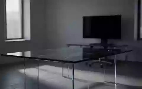 Ein minimalistisch eingerichtetes, dunkles Büro mit einem leeren Konferenztisch und einem ausgeschalteten Computerbildschirm. - Foto: über boerse-global.de
