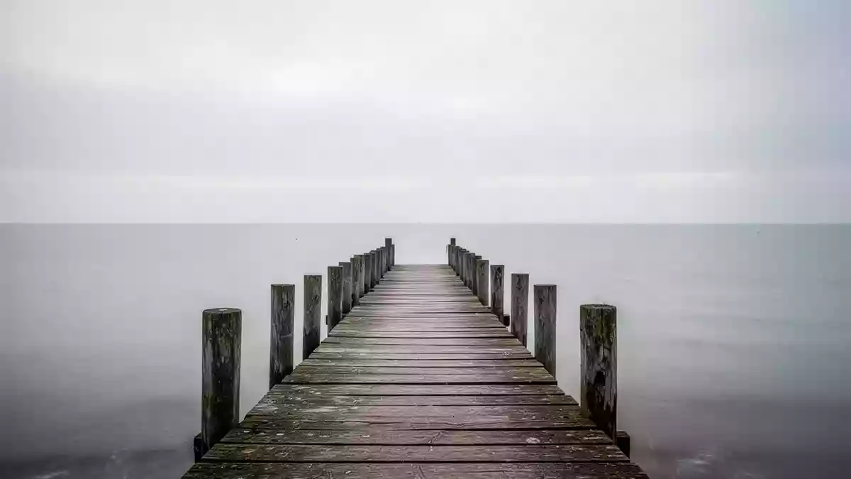 Ein hölzerner Steg an der Ostseeküste unter einem bewölkten Himmel. Illustration mit AI erstellt.