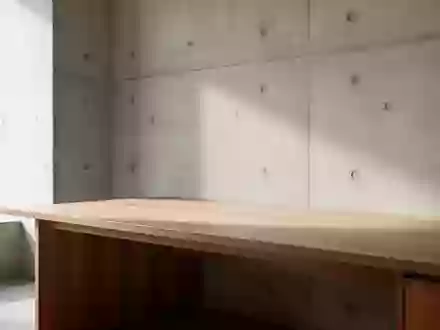 Ein minimalistischer, aufgeräumter Arbeitsbereich mit einer leeren Holzoberfläche und einer schlichten Betonwand bei Tageslicht. - Foto: über boerse-global.de