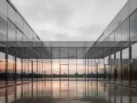 Moderne Architektur aus Glas und Stahl bei Dämmerung mit Fokus auf klare Linien und Lichtreflexionen. - Foto: über boerse-global.de