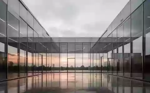 Moderne Architektur aus Glas und Stahl bei Dämmerung mit Fokus auf klare Linien und Lichtreflexionen. - Foto: über boerse-global.de
