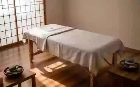 Ein minimalistischer, ruhiger Behandlungsraum für Massagen mit einem hölzernen Massagetisch und natürlichem Licht. - Foto: über boerse-global.de