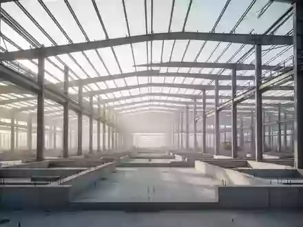 Ein weitläufiger, moderner Industriebau im Rohbau mit freiliegenden Stahlträgern und Betonfundamenten bei natürlichem Licht. - Foto: über boerse-global.de