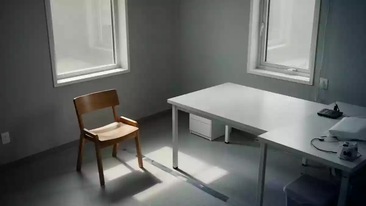 Ein leeres, minimalistisches Behandlungszimmer mit einem hölzernen Stuhl und einem Tisch in ruhigem Tageslicht. Illustration mit AI erstellt.