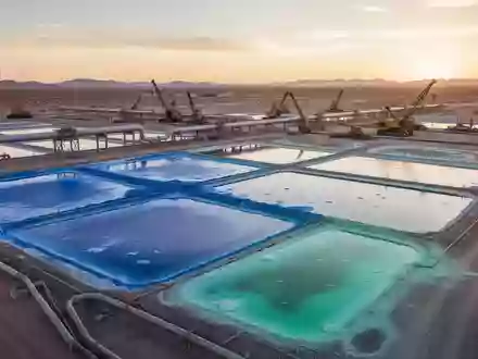 Industrielle Lithium-Extraktionsanlage mit Verdunstungsbecken in einer Wüstenlandschaft bei Sonnenuntergang. - Foto: über boerse-global.de
