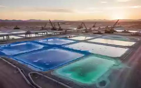 Industrielle Lithium-Extraktionsanlage mit Verdunstungsbecken in einer Wüstenlandschaft bei Sonnenuntergang. - Foto: über boerse-global.de