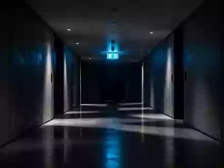 Ein minimalistischer, schattiger Flur mit einem blauen Notausgangsschild an der Wand. - Foto: über boerse-global.de