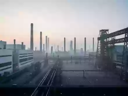 Weitläufige, moderne Industrieanlage in der Morgendämmerung mit großen Fabrikgebäuden und Stahlinfrastruktur. - Foto: über boerse-global.de