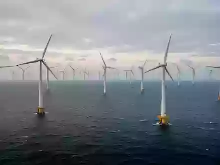 Ein weitläufiger Offshore-Windpark mit zahlreichen Windkraftanlagen auf dem offenen Meer bei Tagesanbruch. - Foto: über boerse-global.de