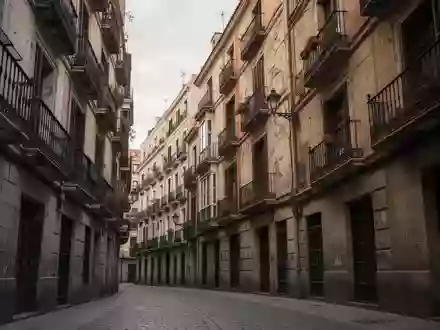 Traditionelle Wohnhausfassaden mit Balkonen in einer engen Gasse in Madrid bei bewölktem Himmel. - Foto: über boerse-global.de