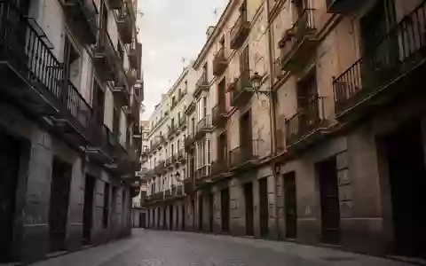 Traditionelle Wohnhausfassaden mit Balkonen in einer engen Gasse in Madrid bei bewölktem Himmel. - Foto: über boerse-global.de