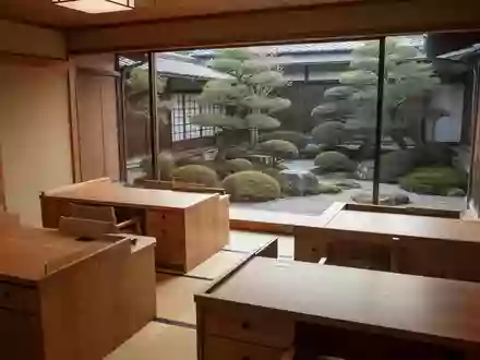Ein minimalistisches, ruhiges Gemeindebüro in Japan mit leeren Holzschreibtischen und Blick auf einen gepflegten Garten. - Foto: über boerse-global.de