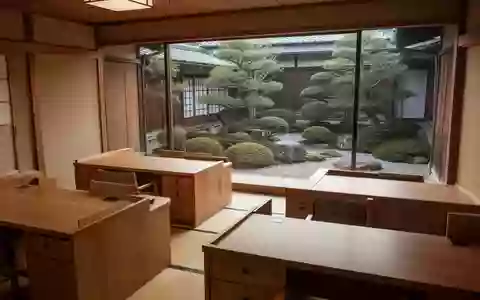 Ein minimalistisches, ruhiges Gemeindebüro in Japan mit leeren Holzschreibtischen und Blick auf einen gepflegten Garten. - Foto: über boerse-global.de