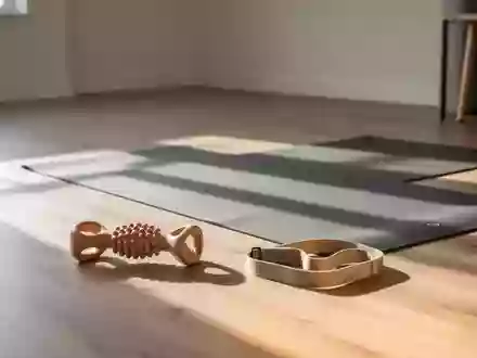 Ein minimalistischer Physiotherapieraum mit einer Yogamatte, einer Massagerolle und einem Widerstandsband auf einem Holzboden. - Foto: über boerse-global.de