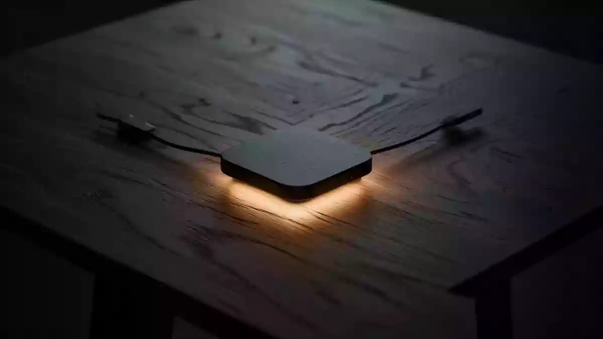 Ein minimalistischer Holztisch mit einem sanften, warmen Lichtschein in der Mitte, der den Prozess der kabellosen Energieübertragung symbolisiert. Illustration mit AI erstellt.