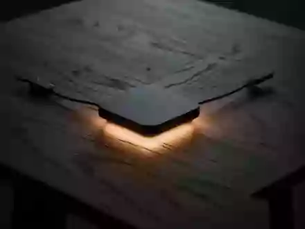 Ein minimalistischer Holztisch mit einem sanften, warmen Lichtschein in der Mitte, der den Prozess der kabellosen Energieübertragung symbolisiert. - Foto: über boerse-global.de