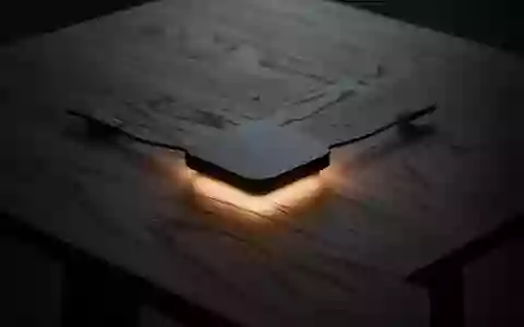 Ein minimalistischer Holztisch mit einem sanften, warmen Lichtschein in der Mitte, der den Prozess der kabellosen Energieübertragung symbolisiert. - Foto: über boerse-global.de