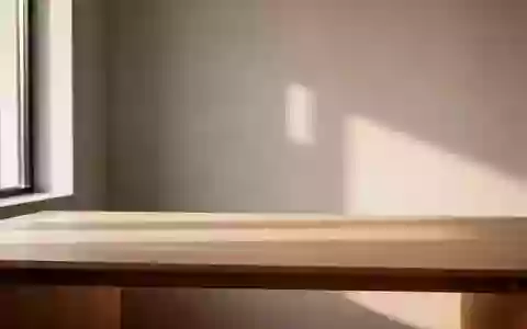 Ein minimalistischer Arbeitsbereich mit natürlichem Tageslicht auf einem leeren Holztisch in einem modernen Raum. - Foto: über boerse-global.de