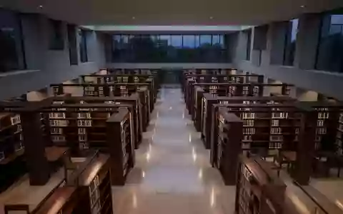 Eine ruhige, moderne wissenschaftliche Bibliothek mit dunklen Holzregalen und minimalistischer Architektur in der Dämmerung. - Foto: über boerse-global.de