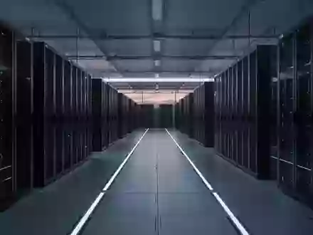 Eine leere, moderne Serverhalle mit langen Reihen dunkler Schaltschränke in kühlem, blauem Licht. - Foto: über boerse-global.de