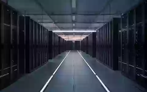 Eine leere, moderne Serverhalle mit langen Reihen dunkler Schaltschränke in kühlem, blauem Licht. - Foto: über boerse-global.de