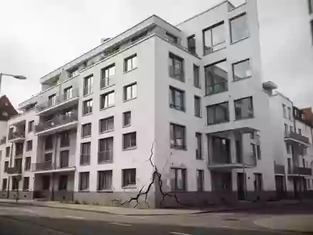 Moderne Wohnanlage mit sichtbaren Rissen in der Fassade an einem bewölkten Tag. - Foto: über boerse-global.de