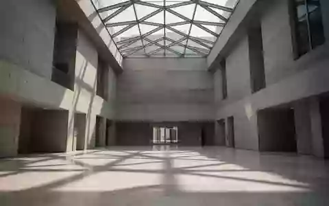 Ein minimalistisches, modernes Regierungsgebäude mit hohen Betonwänden und geometrischen Glasdecken bei natürlichem Tageslicht. - Foto: über boerse-global.de
