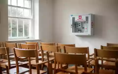 Ein heller Schulungsraum in einem Dorfgemeinschaftshaus mit einem an der Wand montierten Defibrillatorschrank. - Foto: über boerse-global.de