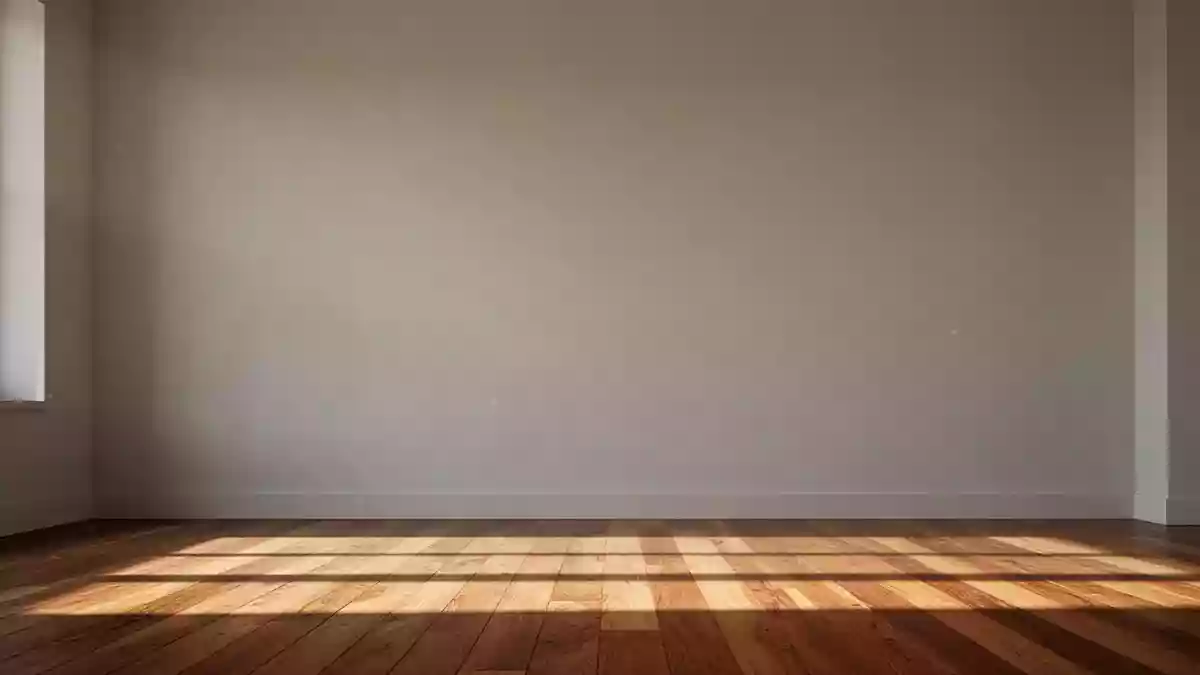 Ein heller, minimalistisch gestalteter Wohnraum mit einer schlichten Wand und Holzboden im sanften Morgenlicht. Illustration mit AI erstellt.