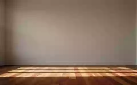 Ein heller, minimalistisch gestalteter Wohnraum mit einer schlichten Wand und Holzboden im sanften Morgenlicht. - Foto: über boerse-global.de