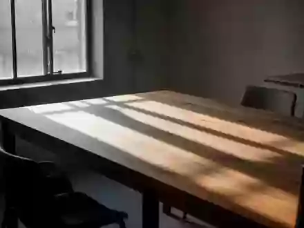 Ein minimalistischer, leerer Esstisch in natürlichem Morgenlicht mit langen Schatten auf einer Holzoberfläche. - Foto: über boerse-global.de
