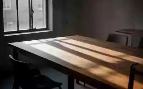 Ein minimalistischer, leerer Esstisch in natürlichem Morgenlicht mit langen Schatten auf einer Holzoberfläche. - Foto: über boerse-global.de
