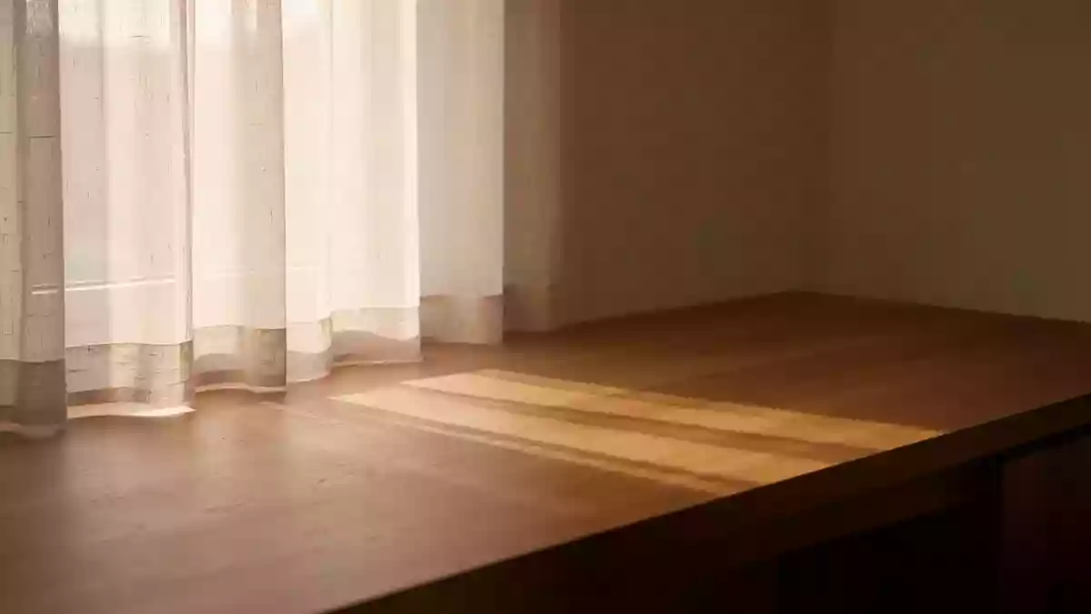 Ein minimalistischer Raum mit weichem Tageslicht, das durch einen Vorhang fällt und eine ruhige, heilende Atmosphäre erzeugt. Illustration mit AI erstellt.