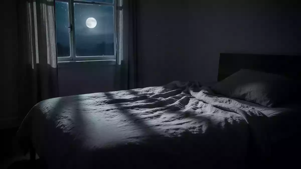 Ein minimalistisch eingerichtetes Schlafzimmer bei Nacht mit sanftem Mondlicht, das auf ein ungemachtes Bett fällt. Illustration mit AI erstellt.