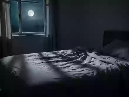 Ein minimalistisch eingerichtetes Schlafzimmer bei Nacht mit sanftem Mondlicht, das auf ein ungemachtes Bett fällt. - Foto: über boerse-global.de