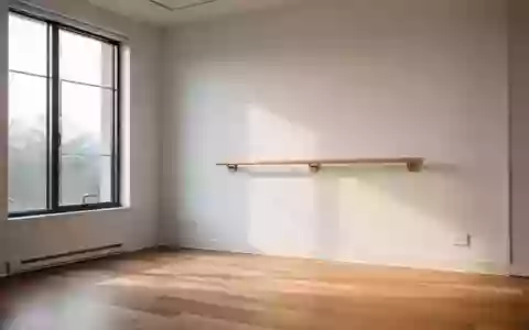 Ein heller, minimalistischer Bewegungsraum mit einem hölzernen Ballett- oder Trainingshandlauf an einer weißen Wand. - Foto: über boerse-global.de