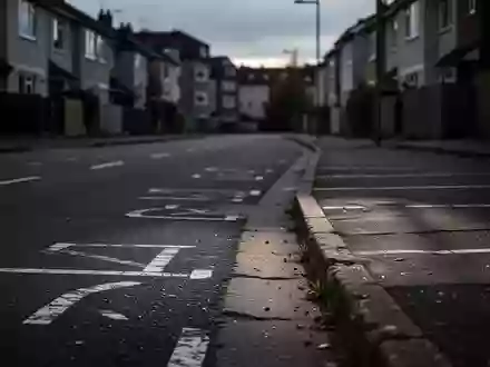Eine leere, verlassene Straße in einem Wohngebiet bei Dämmerung mit sichtbaren Bordsteinkanten und Parkmarkierungen. - Foto: über boerse-global.de