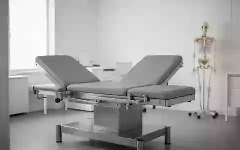 Ein minimalistischer, heller Behandlungsraum mit einer leeren medizinischen Untersuchungsliege und einem anatomischen Modell. - Foto: über boerse-global.de