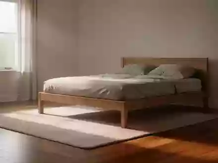 Ein sonnendurchflutetes, minimalistisches Schlafzimmer am frühen Morgen mit einem einfachen Holzbett auf einem Parkettboden. - Foto: über boerse-global.de