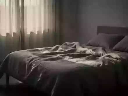 Ein minimalistisch eingerichtetes Schlafzimmer in den frühen Morgenstunden mit sanftem Licht und ungemachtem Bett. - Foto: über boerse-global.de