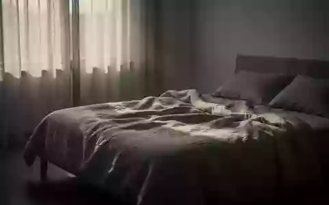 Ein minimalistisch eingerichtetes Schlafzimmer in den frühen Morgenstunden mit sanftem Licht und ungemachtem Bett. - Foto: über boerse-global.de