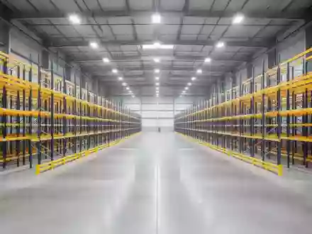 Ein weitläufiges, leeres Lagerhaus mit hohen Regalsystemen und poliertem Betonboden in einer modernen Industriehalle. - Foto: über boerse-global.de