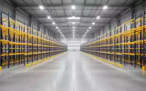 Ein weitläufiges, leeres Lagerhaus mit hohen Regalsystemen und poliertem Betonboden in einer modernen Industriehalle. - Foto: über boerse-global.de