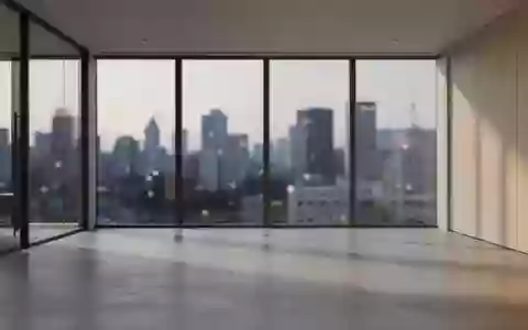 Ein minimalistisches, modernes Büro mit großen Glasfronten und Blick auf eine verschwommene Stadt bei Dämmerung. - Foto: über boerse-global.de