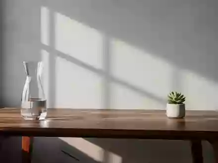 Ein minimalistischer, aufgeräumter Arbeitsplatz mit einer Glaskaraffe und einer Pflanze vor einer schlichten Wand. - Foto: über boerse-global.de